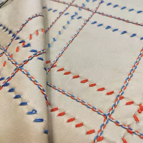 embroidery on fabric with red threads and blue base off-white